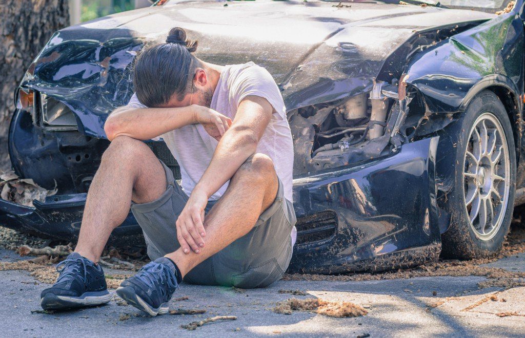 難破した車の前の男